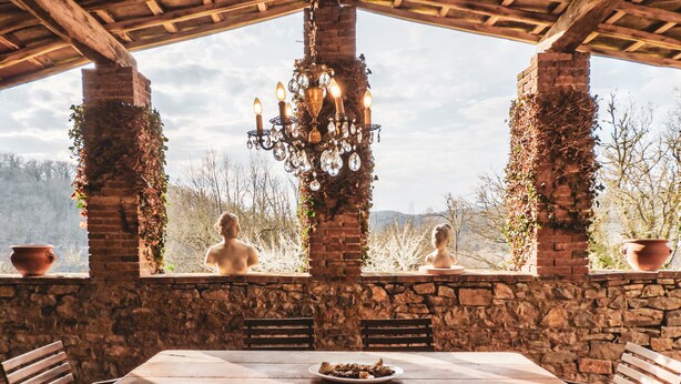 A rustic outdoor dining area with a stone wall, wooden benches, and a table set for two. - Tenuta CorteDomina (Radda in Chianti)