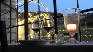 A table set with wine glasses and a candle, viewed through a window with string lights. - Tenuta CorteDomina (Radda in Chianti)