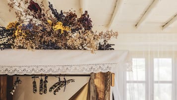 Una habitación con cama, cabecero de encaje y ventana con cortinas traslúcidas.