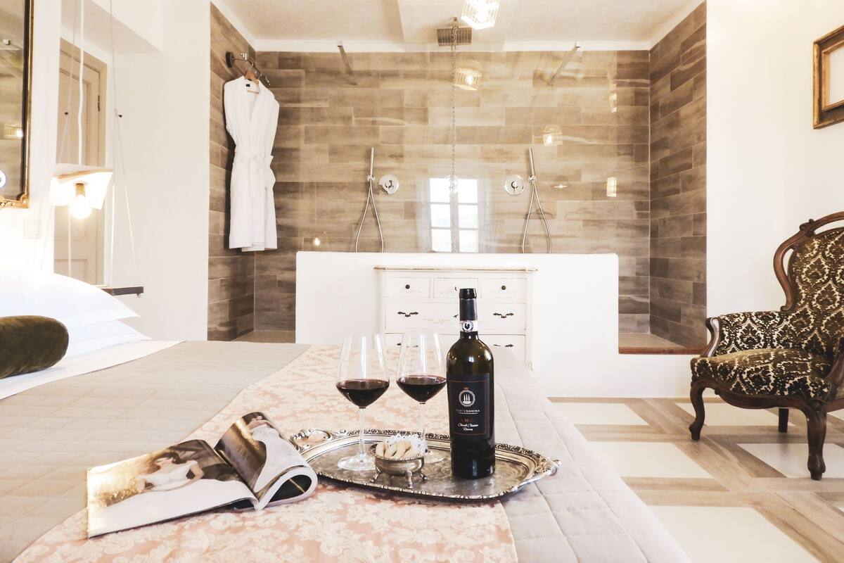 A modern bathroom with a shower, a bathtub, and a vanity with drawers. There is a bottle of wine and glasses on a tray on the floor.