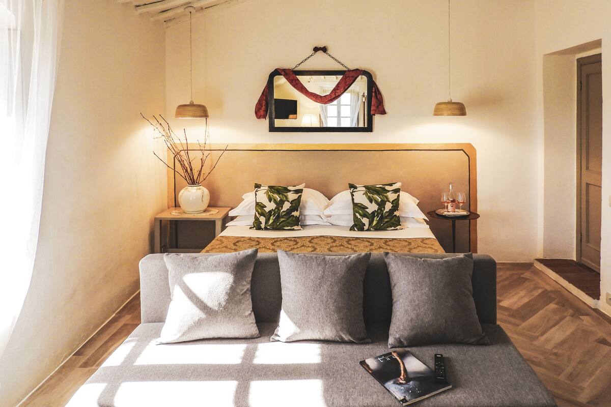 A bedroom with a bed, bedside tables, a mirror, and a hanging red cloth.