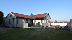 A two-story house with a red-tiled roof, a covered porch, and a small front yard. - Solferie Holiday Home Marthas vei (Kristiansand)
