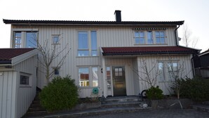 A two-story house with a red-tiled roof, a front door, and a small porch area. - Solferie Holiday Home Marthas vei (Kristiansand)