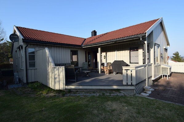 A two-story house with a covered patio, a satellite dish, and a chimney.