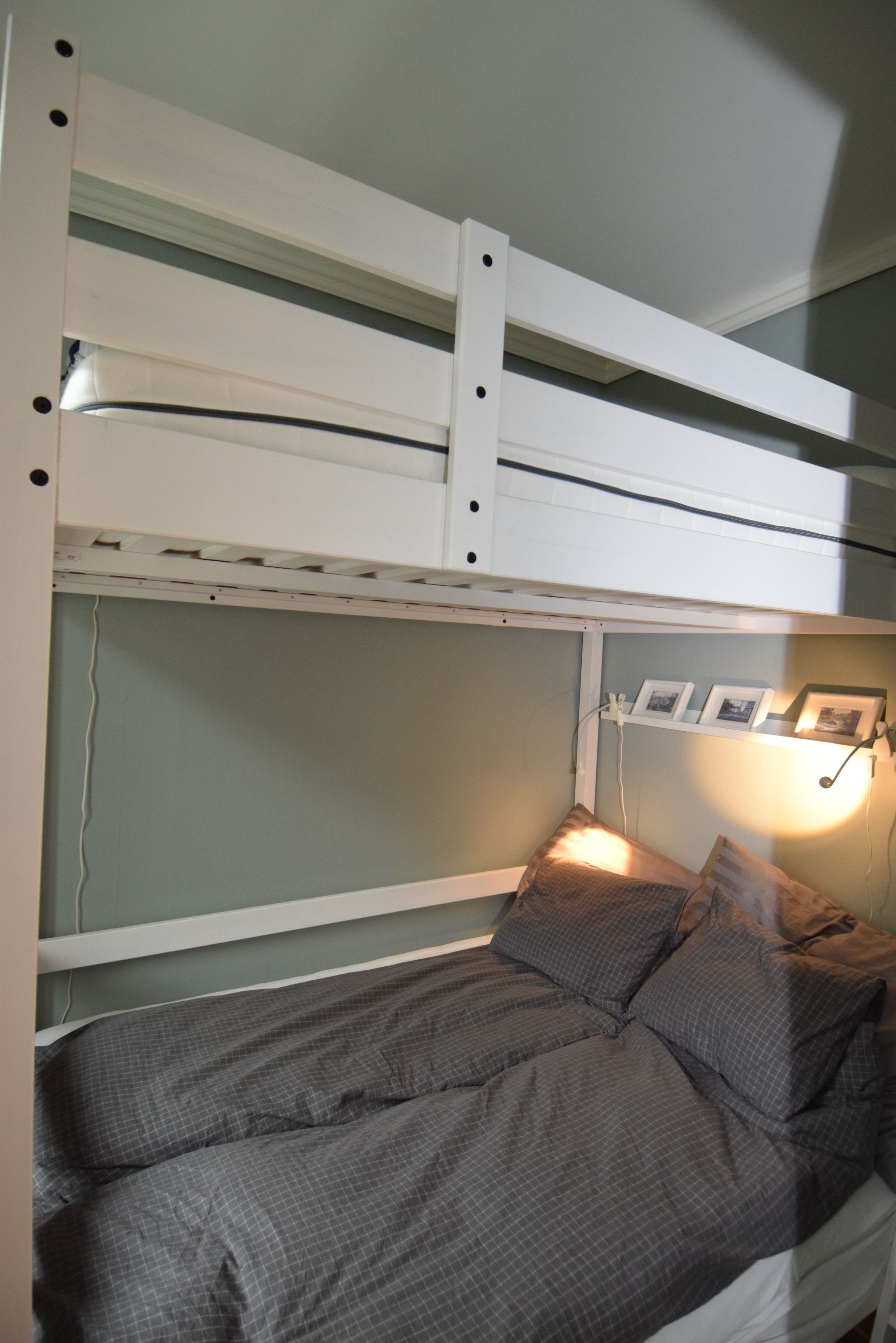 Una cama litera con una cama inferior, un cabecero con estante y una mesita de noche con lámpara.