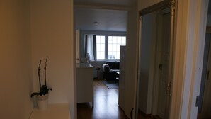 Un couloir qui mène à un salon, où se trouvent un canapé et une fenêtre.