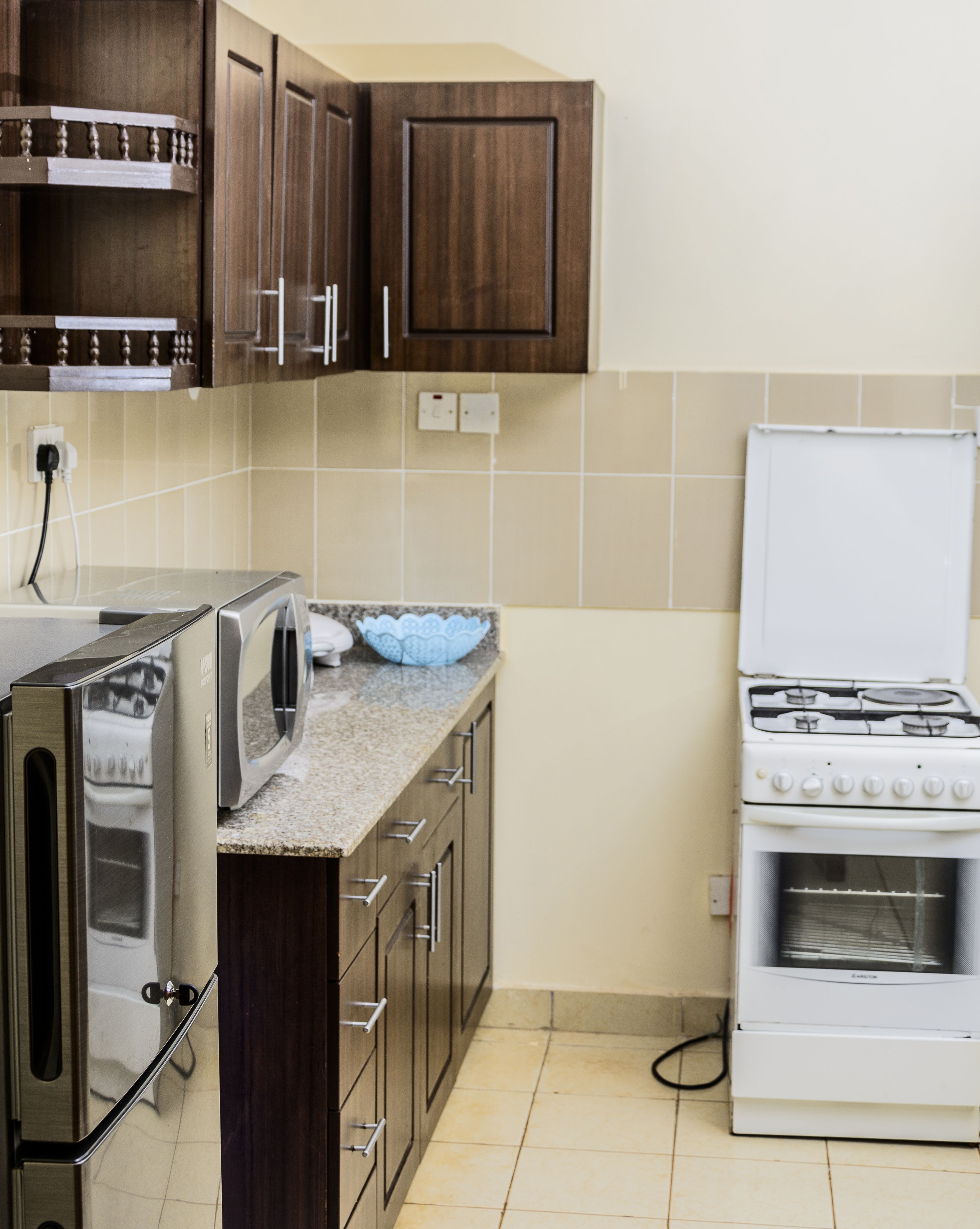Una cocina con armarios de madera, microondas integrado, estufa y una encimera con un bol.