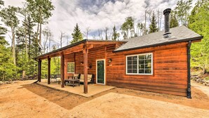 A rustic log cabin with a covered patio, a chimney, and a view of the surrounding forest. - 'Bobcat Trail Cabin' on 3 Acres in Como! (Como)