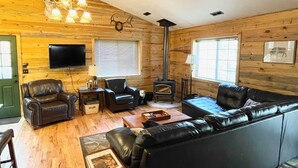 A cozy cabin interior with a fireplace, leather furniture, and wooden walls. - 'Bobcat Trail Cabin' on 3 Acres in Como! (Como)