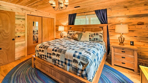 A wooden cabin bedroom with a bed, nightstands, and a chandelier. - 'Bobcat Trail Cabin' on 3 Acres in Como! (Como)