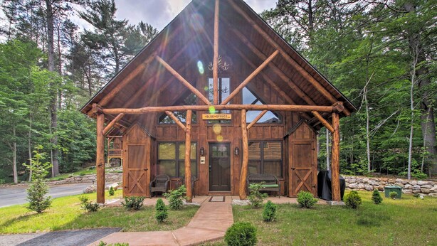 A rustic cabin with a wooden exterior, a front porch, and a stone wall. - Timber Home: Walk to Slopes & N Conway Shops! (North Conway)