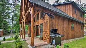 A rustic wooden cabin with a porch, a grill, and a small shed in a forested area. - Timber Home: Walk to Slopes & N Conway Shops! (North Conway)