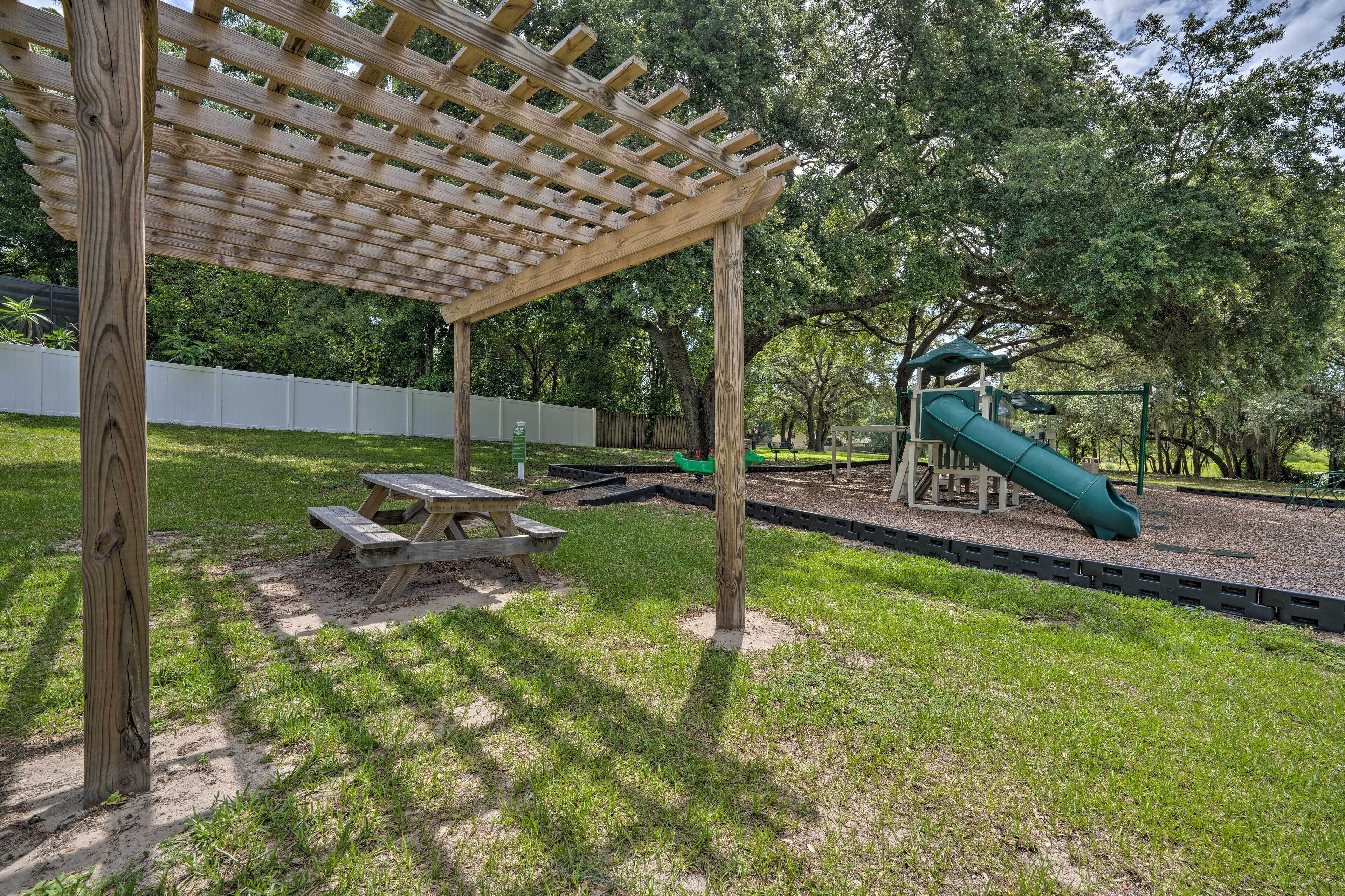 A wooden pergola, picnic table, and playground with a slide.
