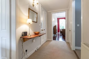 A hallway with a wooden bench, a lamp, and a mirror on the wall.