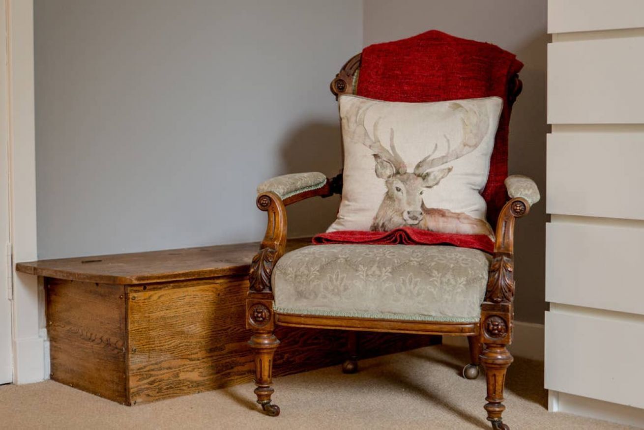 A wooden chair with a cushion featuring a deer design, positioned next to a white cabinet.
