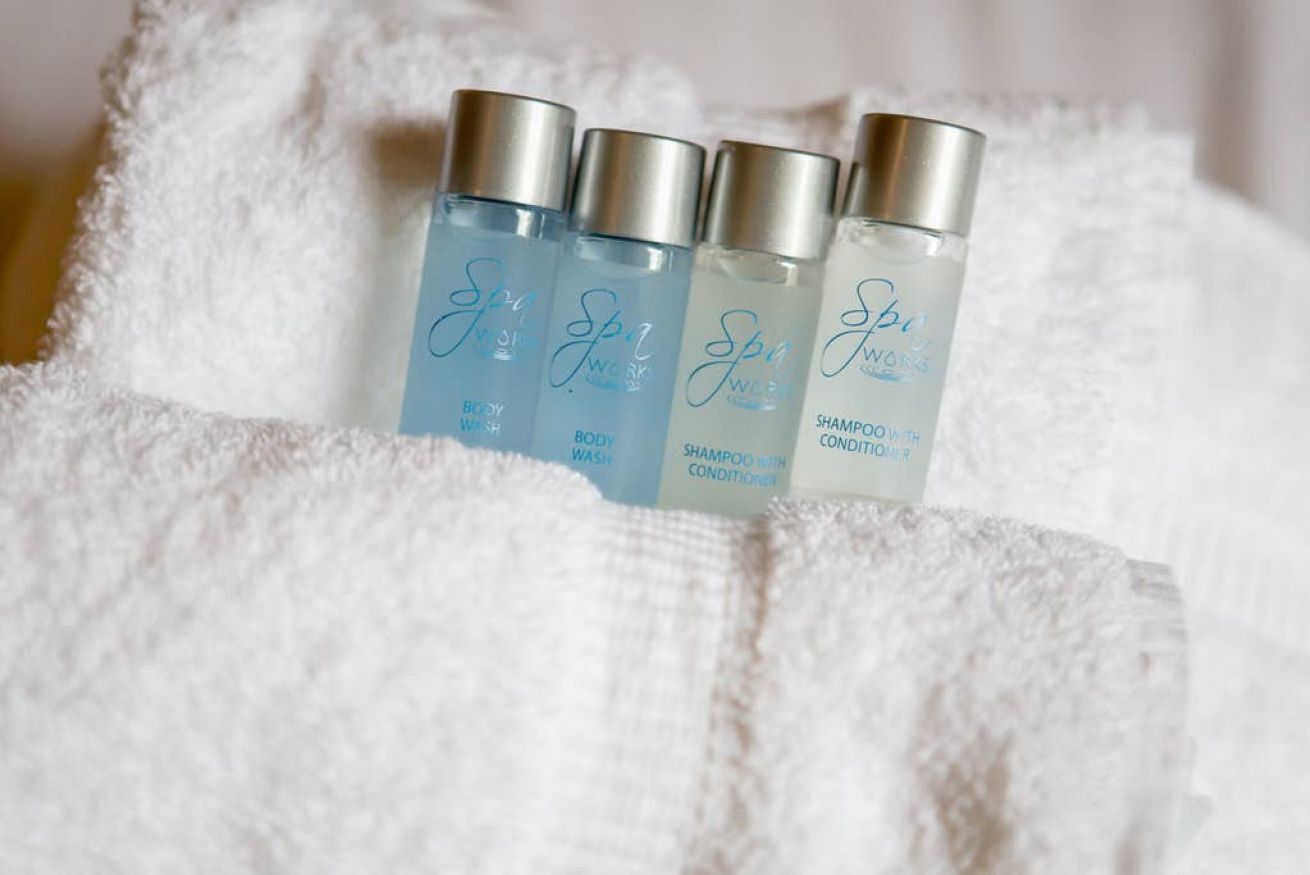 Four bottles of Spa Body Wash and Shampoo with Conditioner on a white towel.