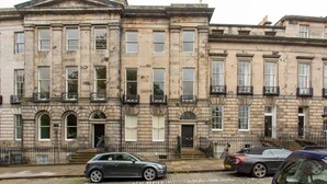 Una hilera de edificios históricos de piedra con ventanas y balcones uniformes.