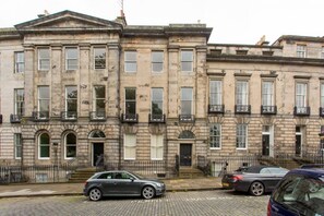 A row of historic stone buildings with uniform windows and balconies.