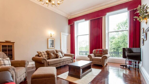 Un salón espacioso con un ventanal grande, chimenea y televisor.