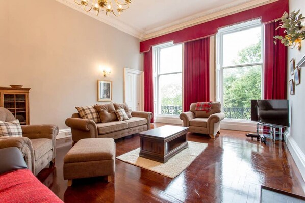 A spacious living room with a large window, a fireplace, and a television.