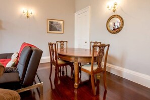 A dining area with a wooden table and six chairs, a black leather sofa, and a white door.