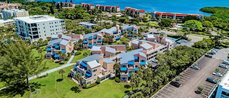 Vista aérea de um resort com vários edifícios, estacionamento e vista para o oceano.