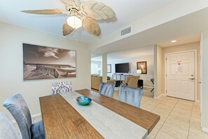 A dining area with a wooden table, chairs, and a ceiling fan.