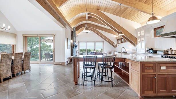Una cocina amplia con una isla grande, vigas de madera en el techo y vistas al exterior.