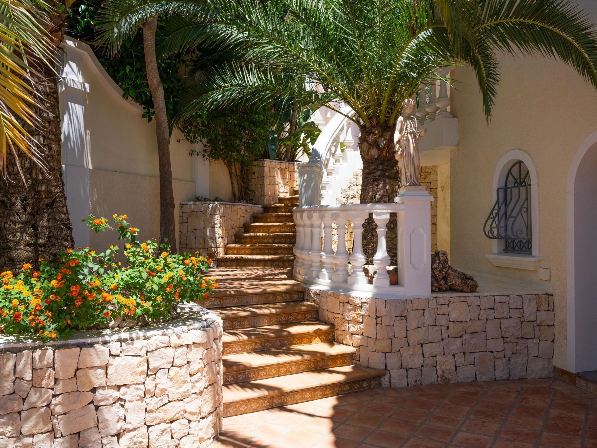 Un escalier en pierre mène à un balcon blanc agrémenté d’une balustrade décorative.