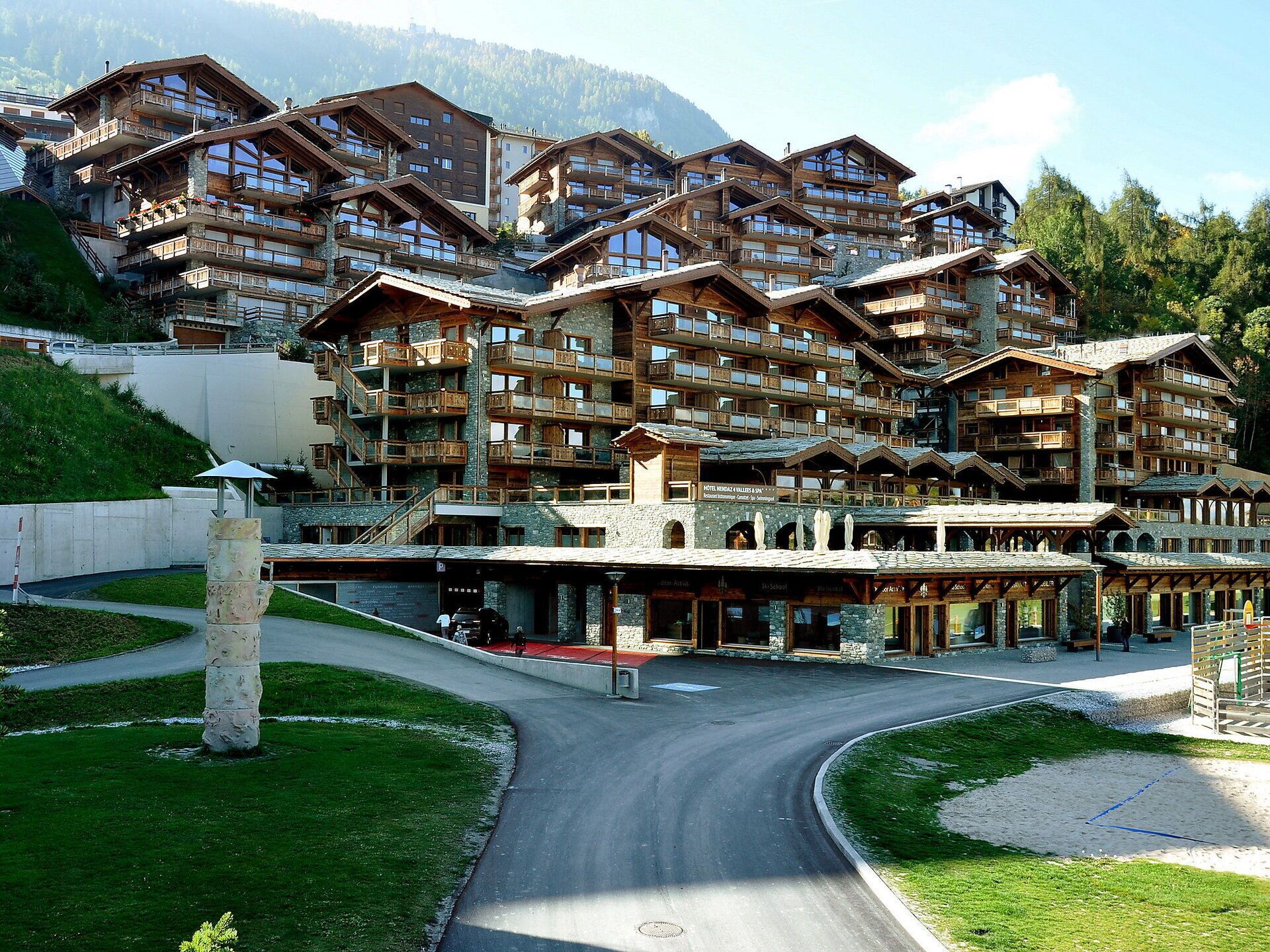 Un hotel a più piani con architettura alpina tradizionale, caratterizzato da balconi e ampie finestre.