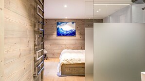 Un dormitorio moderno con pared de madera, una obra de arte colgada, una cama y zona de ducha.