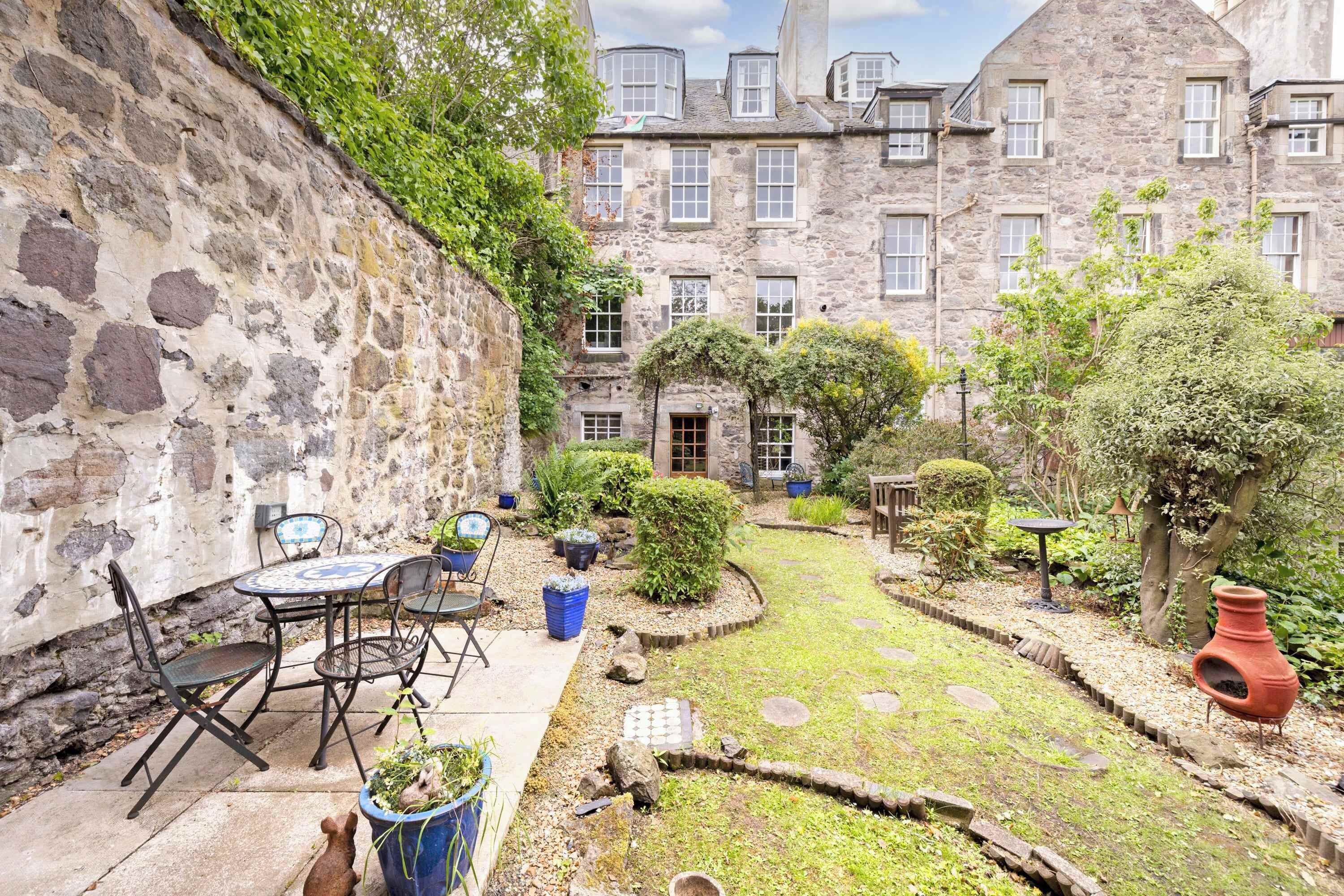 A stone building with a courtyard, outdoor seating, and a small garden.