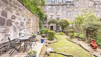A stone building with a courtyard, outdoor seating, and a small garden.