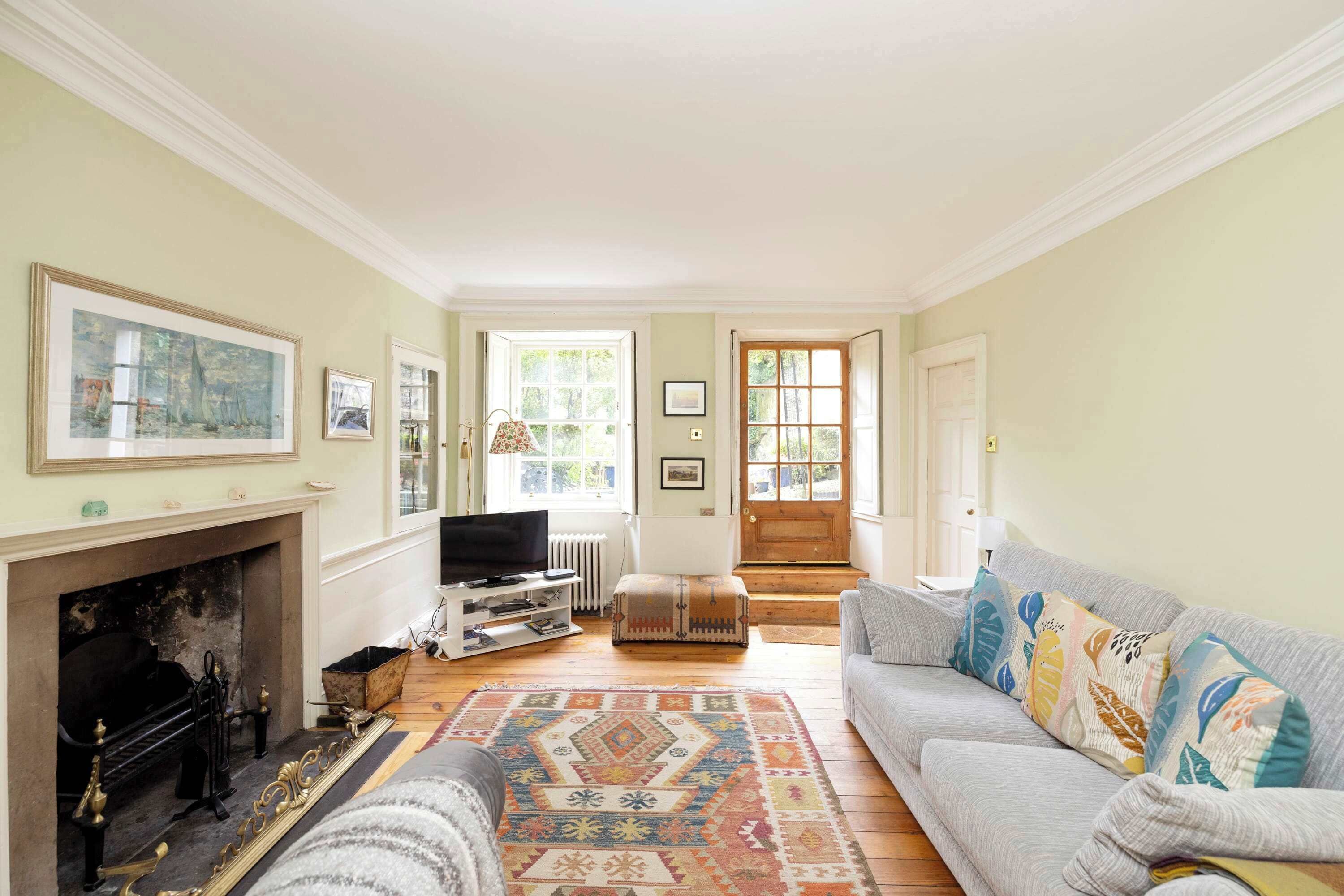 A living room with a fireplace, a sofa, a television, and a patterned rug.