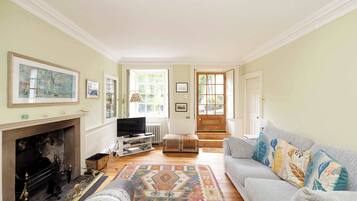 A living room with a fireplace, a sofa, a television, and a patterned rug.