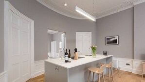Eine moderne Küche mit Kochinsel, Barhocker und einem kleinen Kühlschrank.