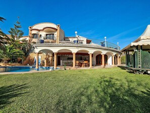 Relax in a spacious outdoor area with a large pool, covered patio, and lawn.