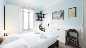 A bedroom with a bed, a desk, a chair, and a bookshelf.