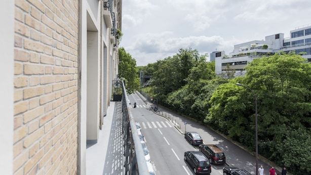 A street view with a brick building, a pedestrian bridge, and cars on the road.