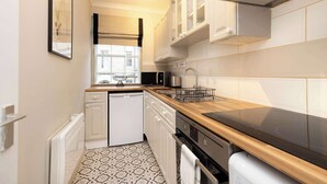 Una cocina moderna con armarios blancos, encimera negra y suelo estampado.