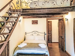 Une chambre à coucher avec un lit, un escalier en bois, une porte et un tableau accroché au mur.