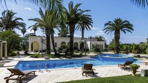 A pool area with lounge chairs, palm trees, and a building with arches. - Stunning private villa with hot tub, A/C, private pool, WIFI, TV, patio and pets allowed (Nardò)