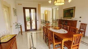 A spacious dining area with a wooden table and chairs, a chandelier, and a view of the outdoors through a glass door. - Stunning private villa with hot tub, A/C, private pool, WIFI, TV, patio and pets allowed (Nardò)