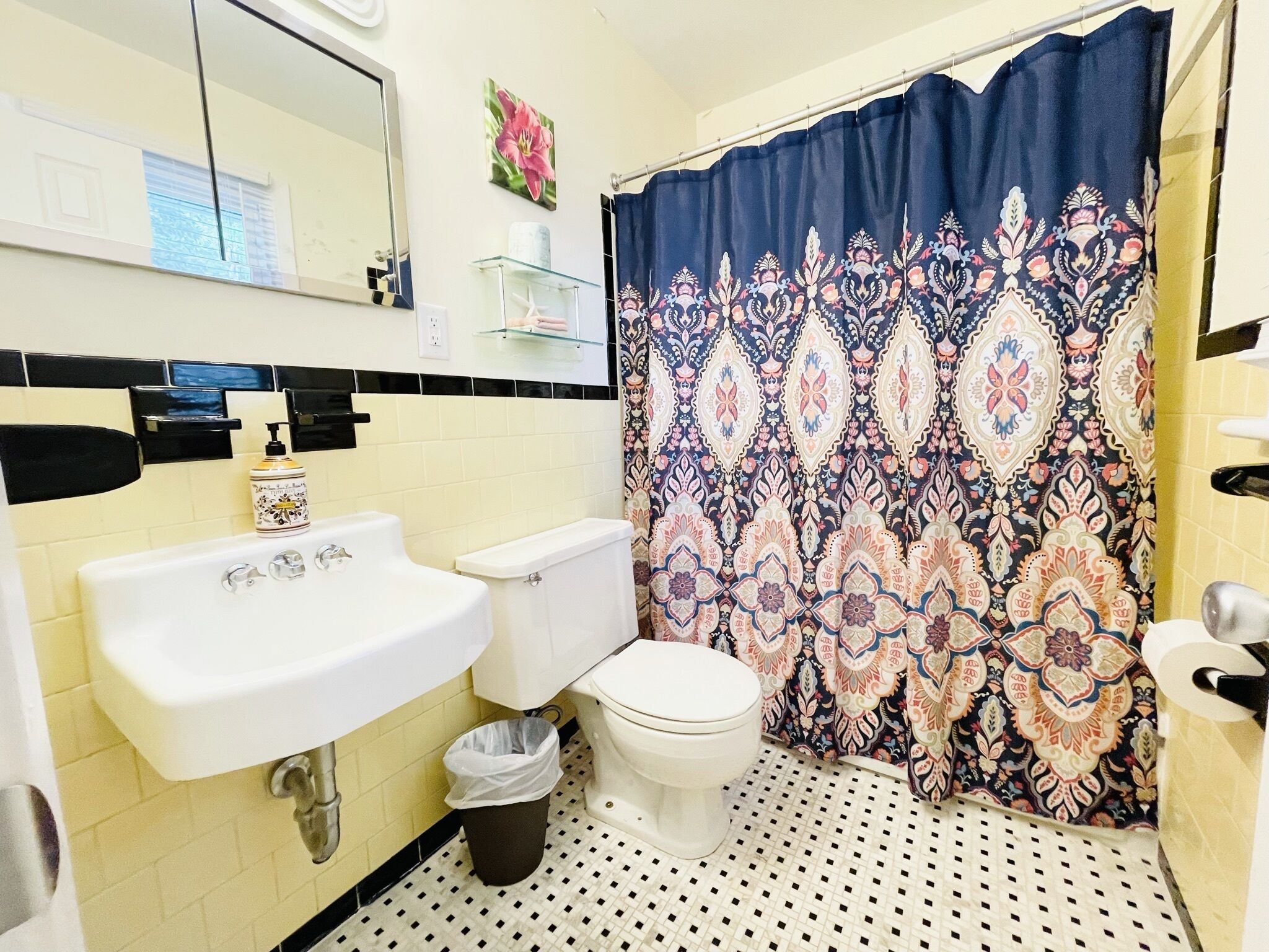 A bathroom with a white sink, toilet, and a patterned shower curtain.