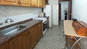 A kitchen with wooden cabinets, a granite countertop, a stainless steel sink, a microwave, a refrigerator, and a wooden bench. - RIVER  - Apartment with sea views Free WiFi (Daimús)