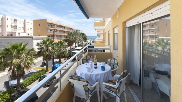 A balcony with a table set for two, chairs, a bottle, and a cup. - RIVER  - Apartment with sea views Free WiFi (Daimús)