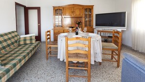 A living room with a dining table, chairs, a sofa, a television, and a cabinet. - RIVER  - Apartment with sea views Free WiFi (Daimús)
