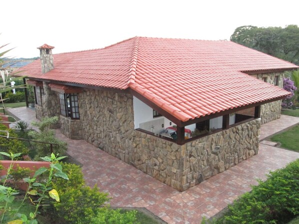 Una casa de piedra con techo de tejas rojas y un porche cubierto.