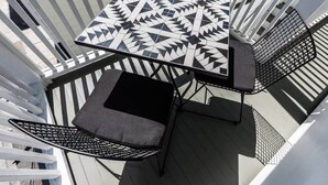 Een balkon met een tafel en twee stoelen, versierd met een geometrisch patroon.