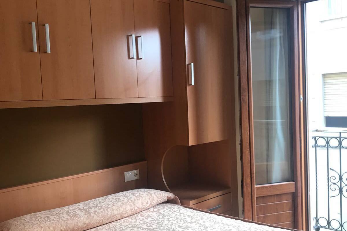 Ein Schlafzimmer mit einem Bett, Holzschränken, einem Fenster mit Blick und einer Deckenleuchte.